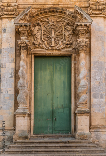 Green front door with stone carving in Ortigia island near Syracuse, Sicily, Italy  © Andrii Shnaider
