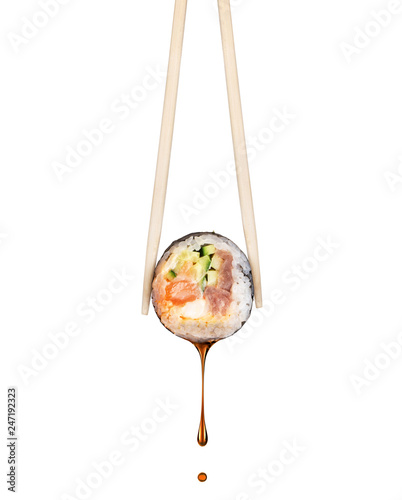 Drop of soy sauce drips from a fresh sushi roll