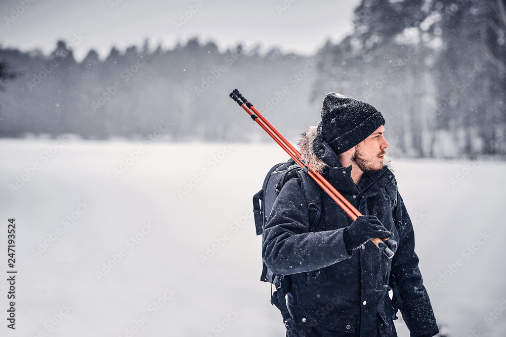 Portrait of a hiker guy with a backpack walking through a winter forest Portrait of a hiker guy with a backpack walking through a winter forest