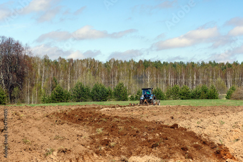 Spring.The old tractor processes agricultural land for seeding.Latvia. 