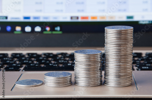 Rising columns of coins near the keyboard on the background of the laptop's on-screen display