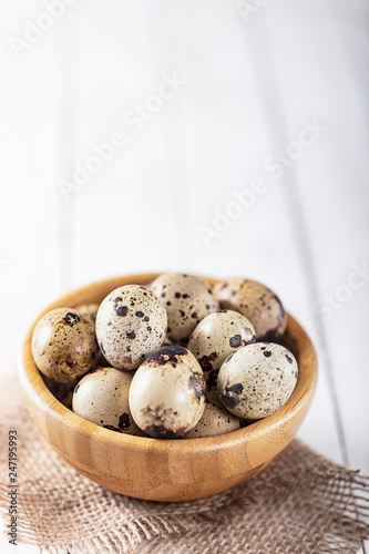 quail eggs in wooden plate over white background