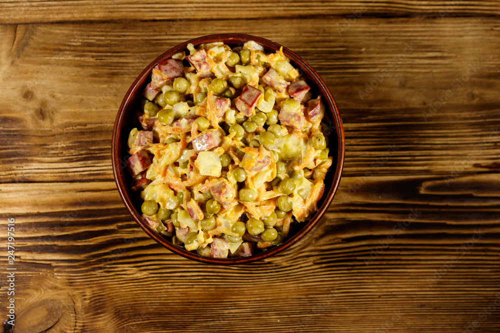 Mayonnaise salad with sausage, green pea, carrot and onion on wooden table Mayonnaise salad with sausage, green pea, carrot and onion on wooden table