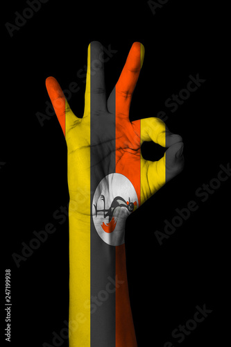 Hand making Ok sign, Uganda flag painted as symbol of best quality, positivity and success - isolated on black background photo