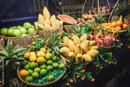 Exotic fruits at street night market in Khao Lak, Thailand. Dragon fruit, lime, mango, orange, pineapple, apple for sale in the bucket.