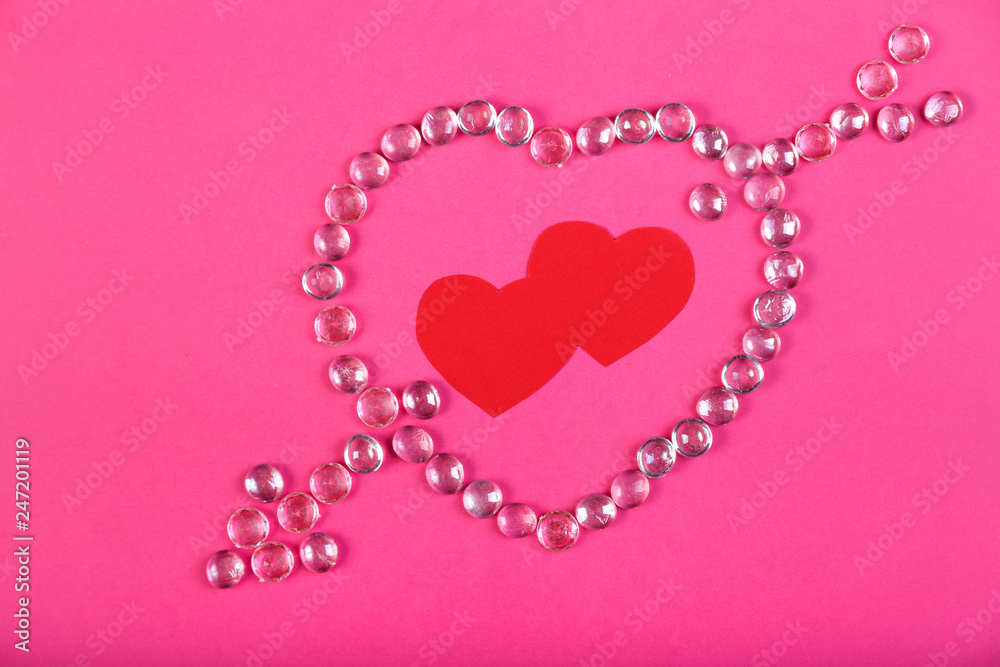 Heart lined with beads with an arrow on a pink background with a heart in the middle.