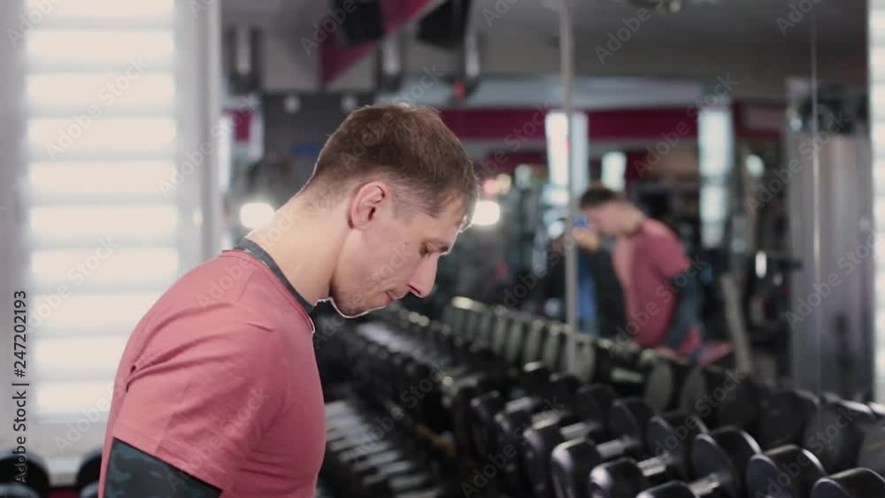 Handsome sporty man picks up dumbbells from the racks in the gym. Handsome sporty man picks up dumbbells from the racks in the gym.