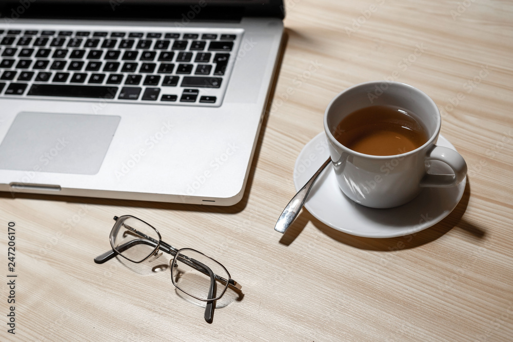 Desk with laptop, eyeglasses and a cup of tea on a wooden table - image Desk with laptop, eyeglasses and a cup of tea on a wooden table - image