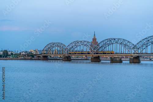 View of Cityscape with Railway Bridge and Train on it in Riga, Latvia, on Blue Hour, Twilight with a Free Space for Text, Concept of Travels