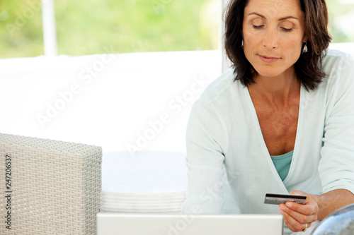 pretty middle aged woman using credit card and laptop at home
