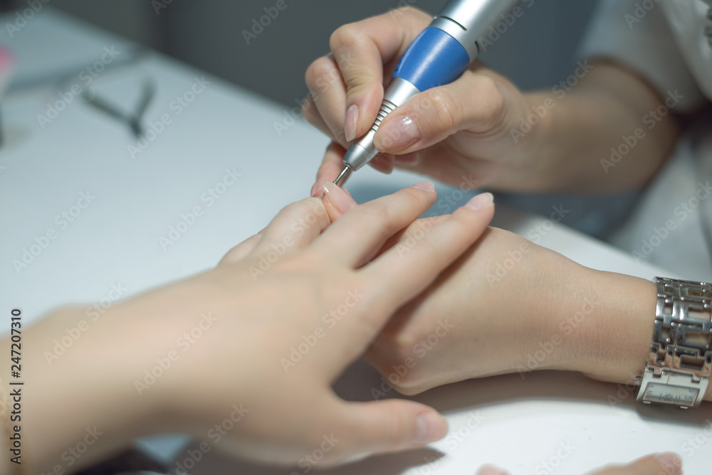 Manicurist is performing a hardware manicure in a nail salon. Nail care concept. Manicurist is performing a hardware manicure in a nail salon. Nail care concept.