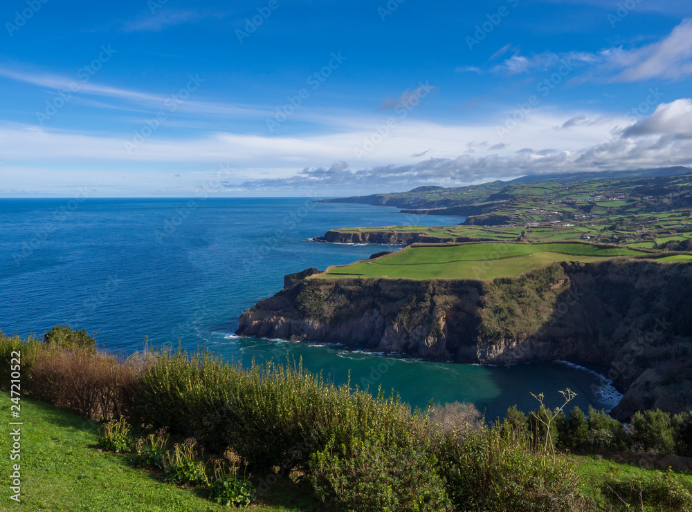 green fields pasture and coastal cliffs and blue ocean and sky horizon at north coast of sao miguel island, Azores, Portugal