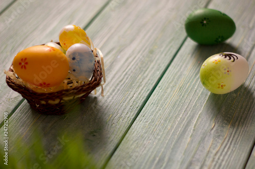 Easter card with painted eggs on the wooden table, with flower and grass