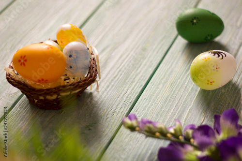 Easter card with painted eggs on the wooden table, with flower and grass