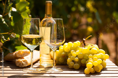 Fototapeta Naklejka Na Ścianę i Meble -  glass of White wine ripe grapes and bread on table in vineyard