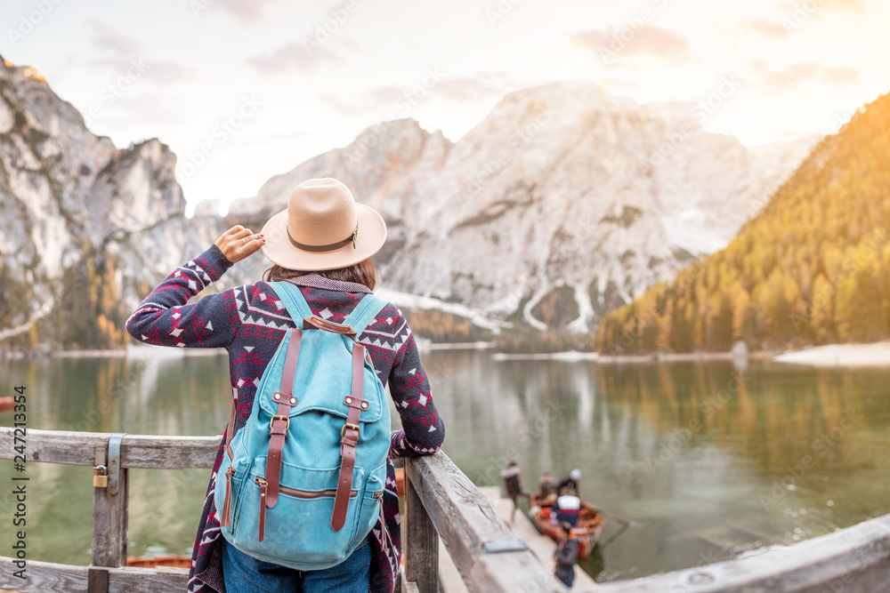 Asian woman traveler on the shore of the famous tourist lake Braies in the Dolomites Alps, Italy. The concept of travel and adventure in the mountains at autumn season