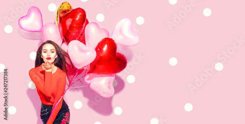 Valentine's Day. Beauty girl with colorful air balloons having fun over pink polka dots background
