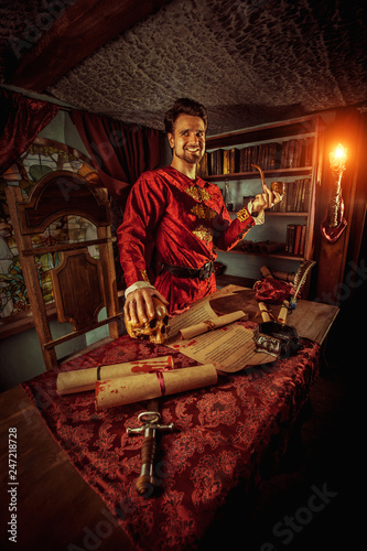 Smiling medieval grandee with the smoking pipe in one hand and skull in another.
