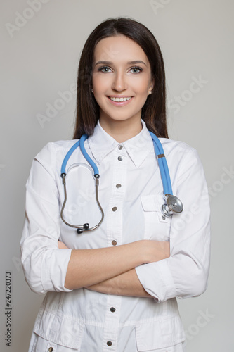 Young female doctor in uniform with stethoscope. Gray background.