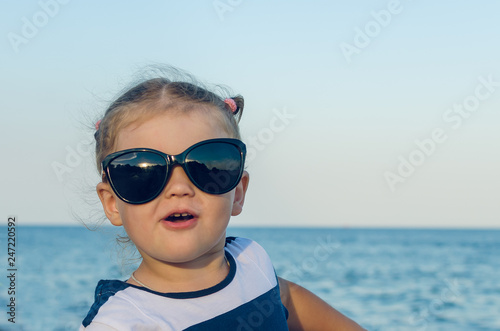 Portrait of a little girl in sunglasses by the sea
