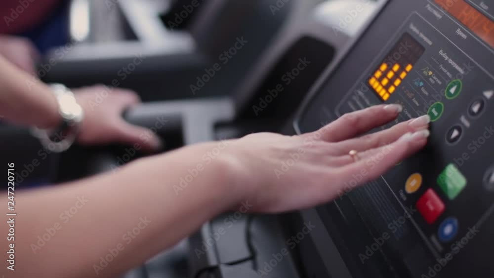 Very beautiful and sexy fitness model sets up a treadmill at the gym