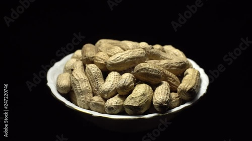 Raw Inshell Peanuts in Rotation. peanuts in shell. Snack closeup.   Peanuts in a bowl. Selective focus. black background. Studio shot. Healthy food concept.