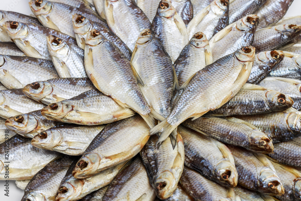 Large heap of dried salted sea roach laid out in the form of a circle on a white background. Close-up