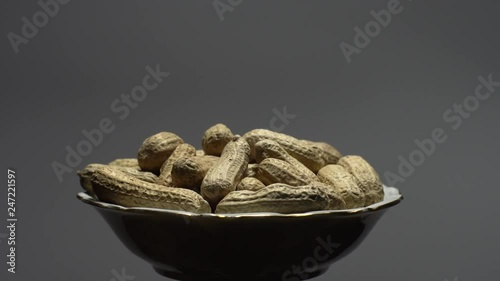 Raw Inshell Peanuts in Rotation. peanuts in shell. Snack closeup.   Peanuts in a bowl. Selective focus. grey background. Studio shot. Healthy food concept.