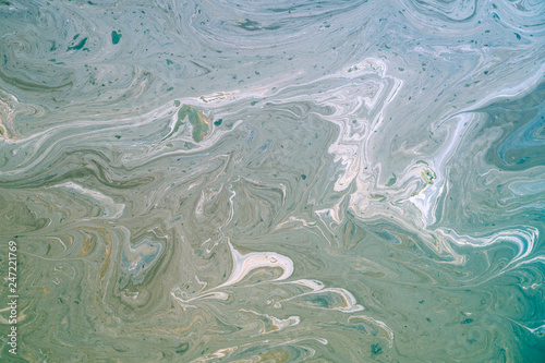 Dirty oily film on the surface of the turquoise sea on the beach