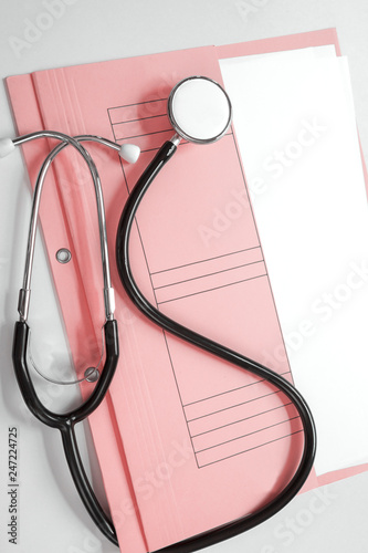 Medical patient file with stethoscope on white background photo