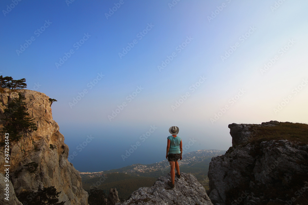 Girl in a hat on the edge of a cliff