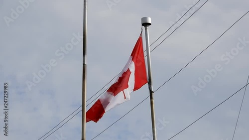 4K Canadian Flag Blowing In The Wind Amonst Power Lines And White Clouds In Blue Sky photo