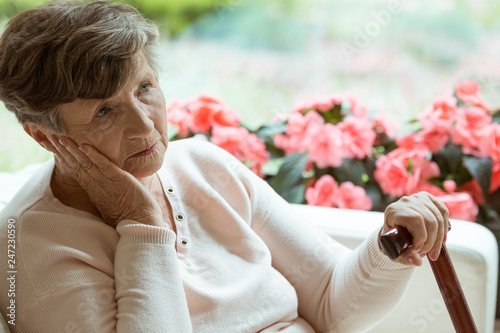 Sad old lady with cane sitting alone at nursing home waiting for her grandchildren