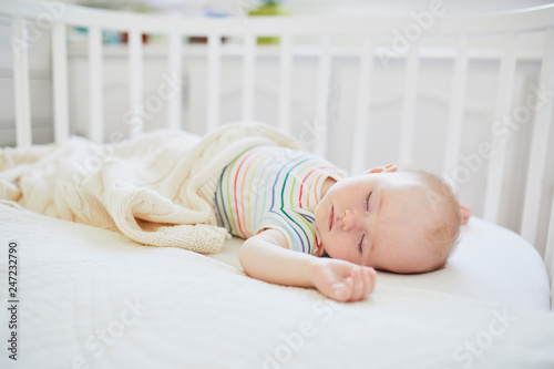 Baby sleeping in co-sleeper crib attached to parents' bed photo