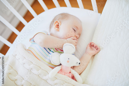 Baby sleeping in co-sleeper crib attached to parents' bed photo