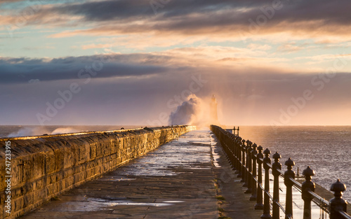 Stormy sea crashing over Tynemouth Pier, Tyneside, Engalnd, UK . In early morning light and sunrise.