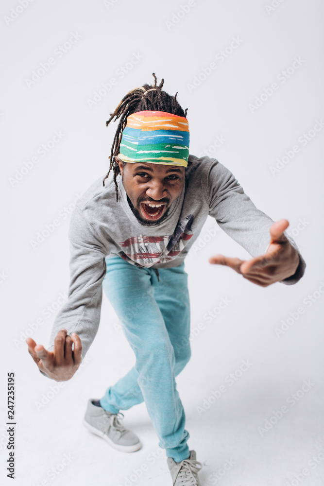 Portrait of a smiling black young model in a gray sweater and blue pants on a gray background Portrait of a smiling black young model in a gray sweater and blue pants on a gray background