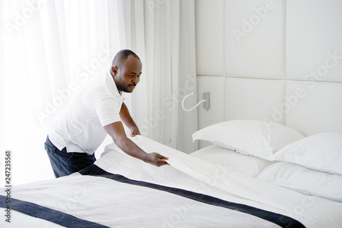 Tablou pe pânză Maid making bed in hotel room