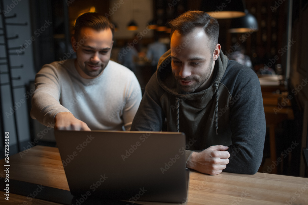 Two confident young businessmen working at laptop. Two confident young businessmen working at laptop.