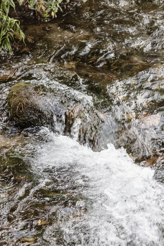 Background image of running fresh water in a river over riverstones.