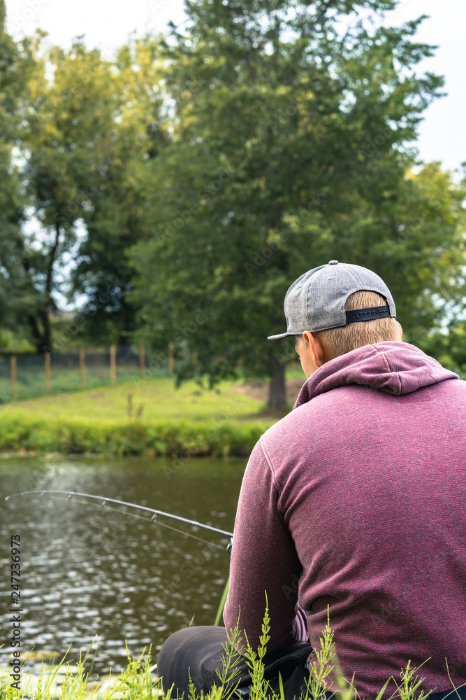 Photo of Millennial with Purple Hoodie and Grey Hat Fishing - Spending Quality Leisure Time, Concept of Educated Generation Member.