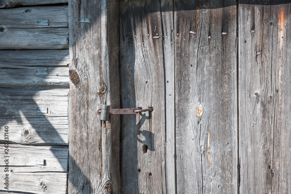 Rusty lock on the wooden doors. Lock on the door of an old farmhouse. Village style. Close-up. Wooden texture. Natural wood background. Rusty lock on the wooden doors. Lock on the door of an old farmhouse. Village style. Close-up. Wooden texture. Natural wood background.
