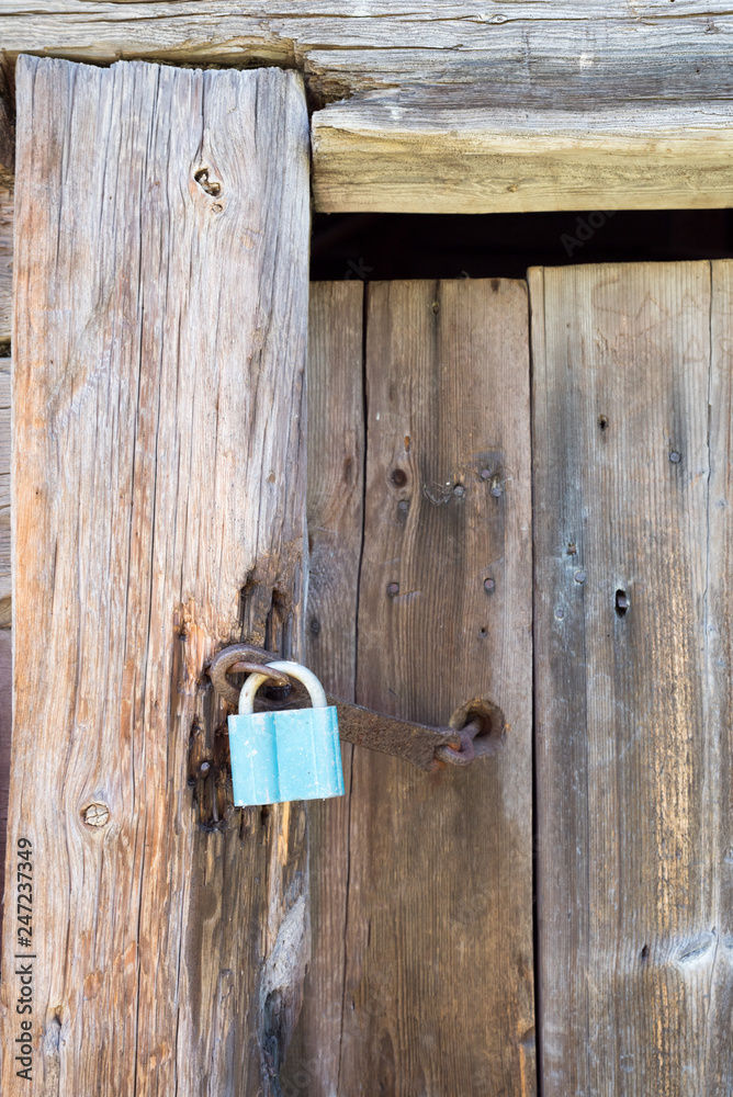 Rusty blue lock on the wooden doors. Lock on the door of an old farmhouse. Village style. Close-up. Wooden texture. Natural wood background.
