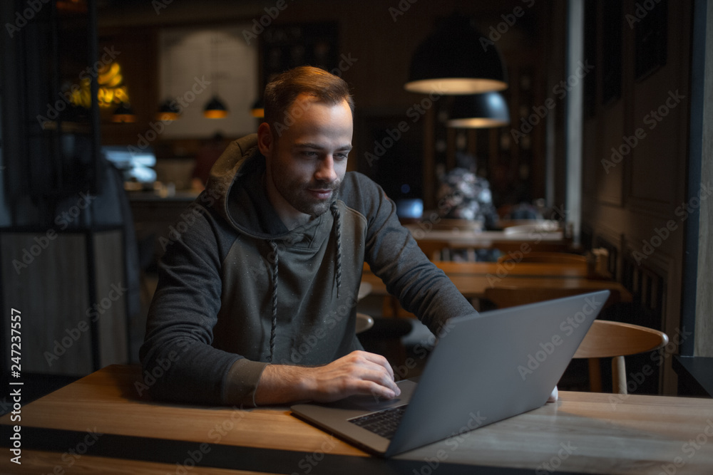 Young man working at laptop in cafe. Young man working at laptop in cafe.