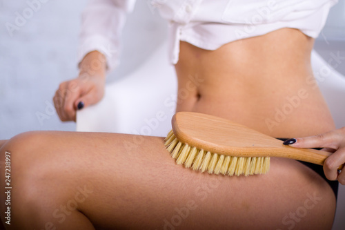 Cosmetology, grooming, Spa cosmetic products, beauty and bikini concept. closeup Woman in black panties makes massage legs with wooden soft massage brush for body and legs