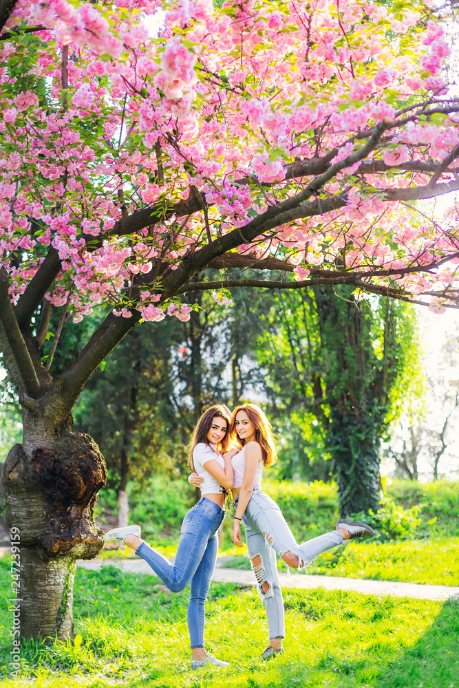 Naklejka premium two girls hug and raised their feet in the park with japanese ch