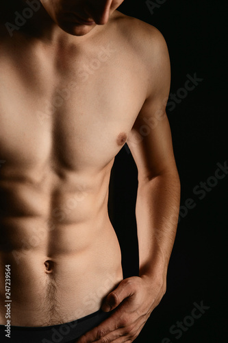 pumped handsome male press. Male athletic body closeup on black background.