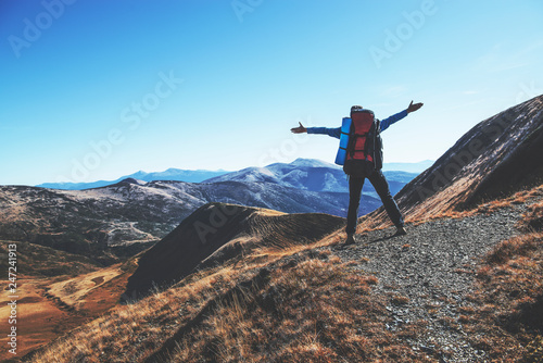 Happy traveller stands on the top of the mountain, with raised arms