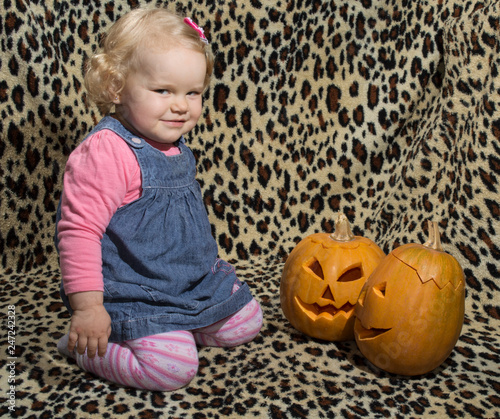 a little blonde girl is interested in two cut for halloween pumpkins