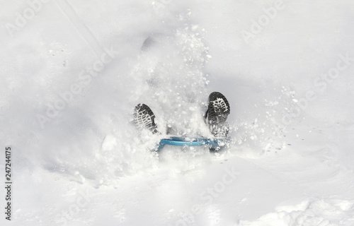 young child sliding in snow during winter